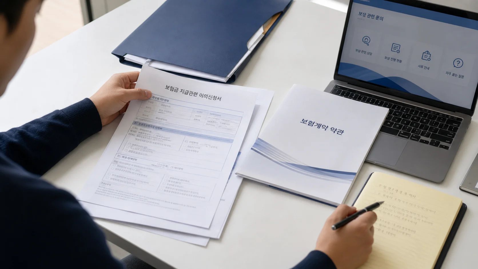 보험금 이의신청서와 보험계약 약관을 함께 확인하는 장면